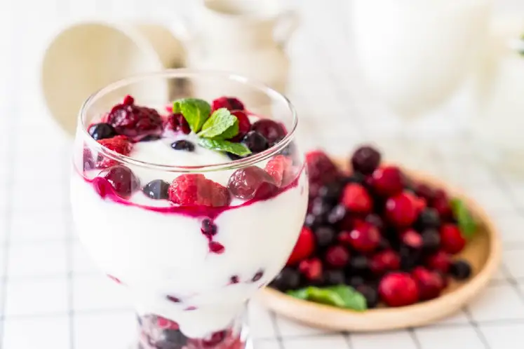 A glass filled with a colorful smoothie made with mixed berries, banana, Greek yogurt, almond milk, and chia seeds, surrounded by fresh berries, representing the ingredients of the Berry Blast Smoothie recipe.