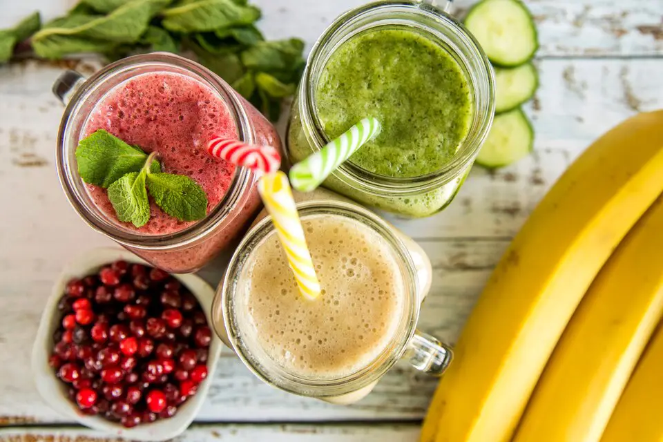 A variety of colorful smoothies in glasses, surrounded by fresh fruits and ingredients, representing healthy weight gain through delicious smoothie recipes.