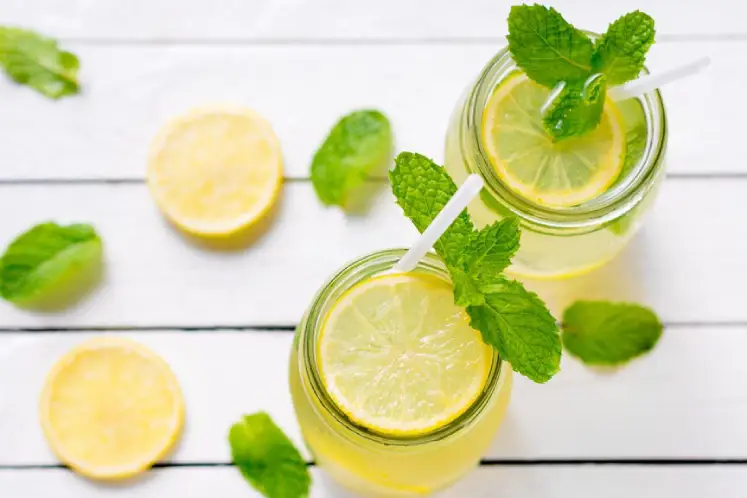 A glass pitcher filled with water infused with slices of lemon and fresh mint leaves.