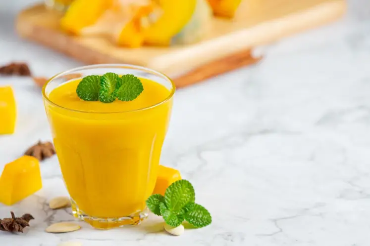 A glass filled with a creamy smoothie featuring pineapple, mango, banana, coconut milk, and spinach, garnished with a pineapple wedge and umbrella, representing the ingredients and tropical theme of the Tropical Paradise Smoothie recipe.