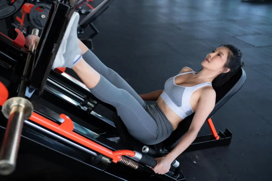 A woman performing a leg press on a machine, emphasizing correct technique and form for lower body strength.