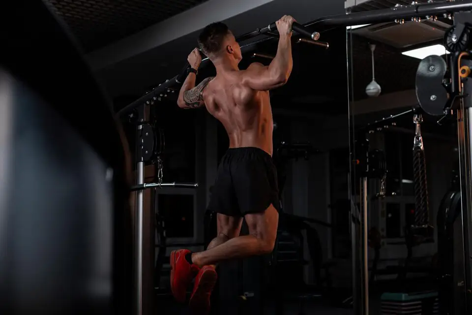 A man performing a pull-up on a horizontal bar, focusing on correct form and technique for upper body strength.