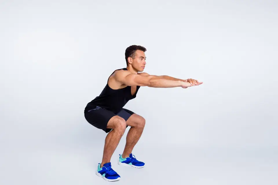 A man performing a squat, focusing on correct posture and leg muscle development.