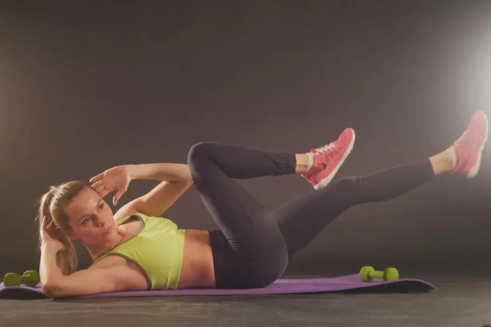 A woman performing bicycle crunches, an effective exercise to target and reduce belly fat.