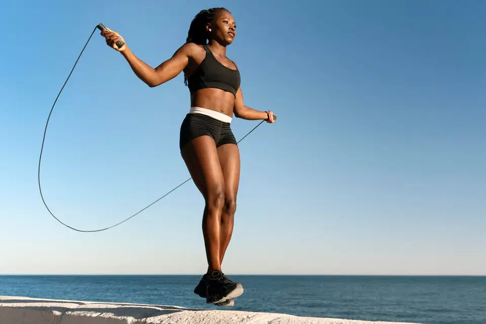 Young woman jumping rope, engaging in a cardio workout to burn calories and improve fitness.