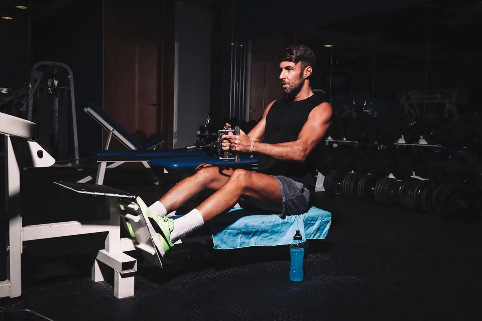 Person rowing on a rowing machine in a gym, demonstrating a full-body cardio exercise to promote weight loss and fitness.