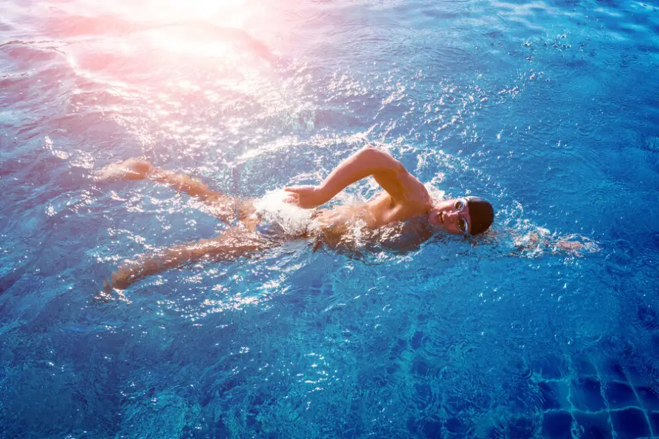 Person swimming freestyle in a pool, focusing on a low-impact exercise for weight loss and muscle toning.