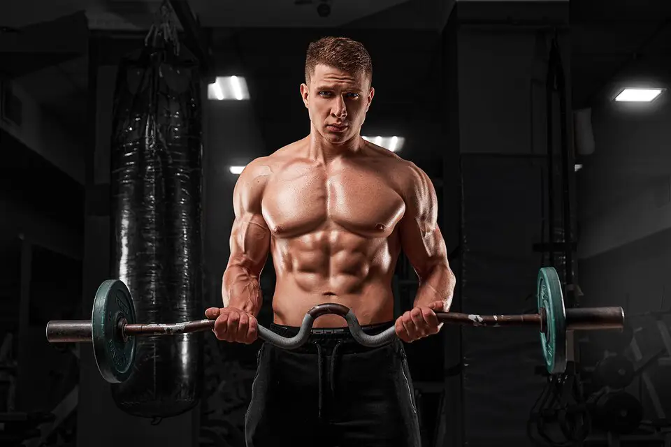 A bodybuilder performing a barbell workout in a gym, illustrating the importance of strength training in fitness fundamentals.