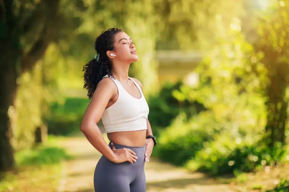 A woman in athletic wear enjoying a sunny outdoor workout, symbolizing physical and mental well-being through regular exercise and mindfulness, highlighting health and wellness.