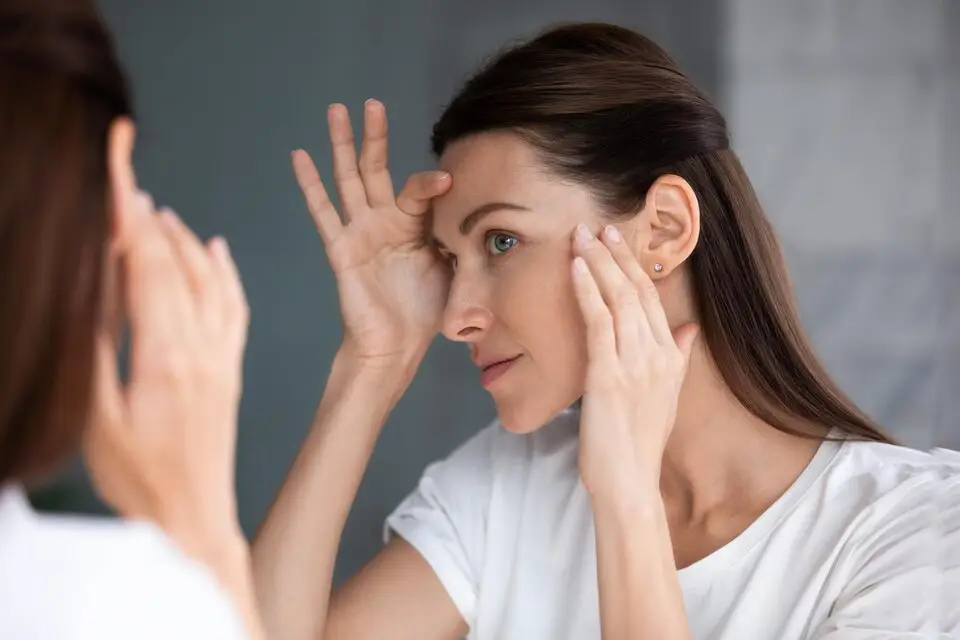 Woman inspecting small white spots on her skin, a potential sign of vitamin deficiency, highlighting the connection between nutrition and skin health.